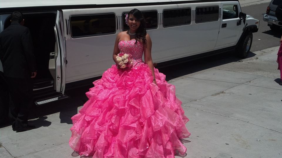 young woman celebrating her quinceanera standing next to hummer limo