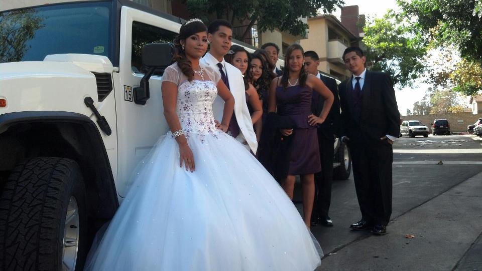 Young woman looking stunning in classic white chiffon dress with friends and the white hummer limo from a plus limos