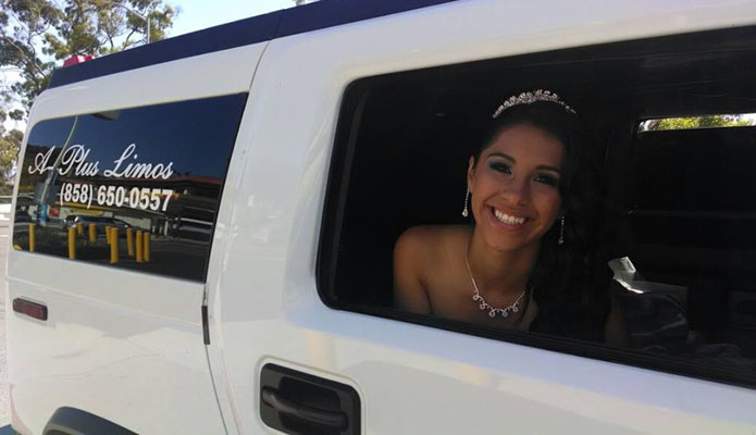 young woman dressed in formal gown looking out a window of a white hummer limousine