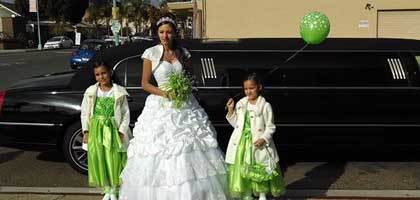 young woman celebrating her quinceanera with two little girls standing next to hummer limo