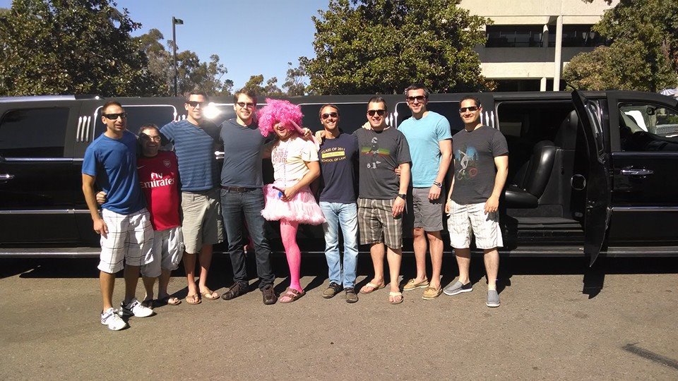 9 buddies smile standing next to escalade limo in San Diego before a bachelor party
