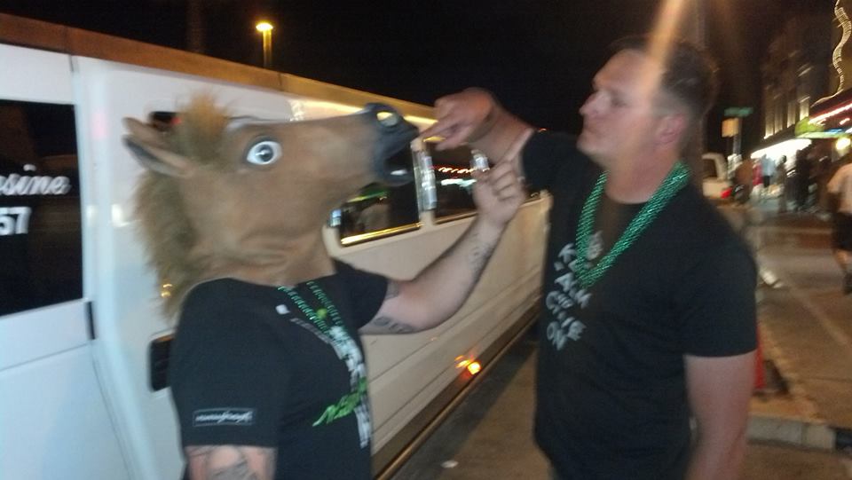 Bachelor with horse head mask and best man joking next to white hummer stretch limo in San Diego